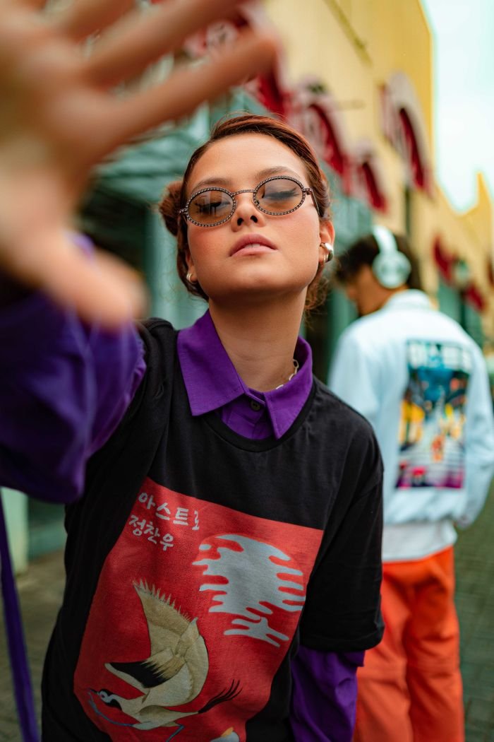 Stylish young woman in streetwear posing with attitude outdoors.