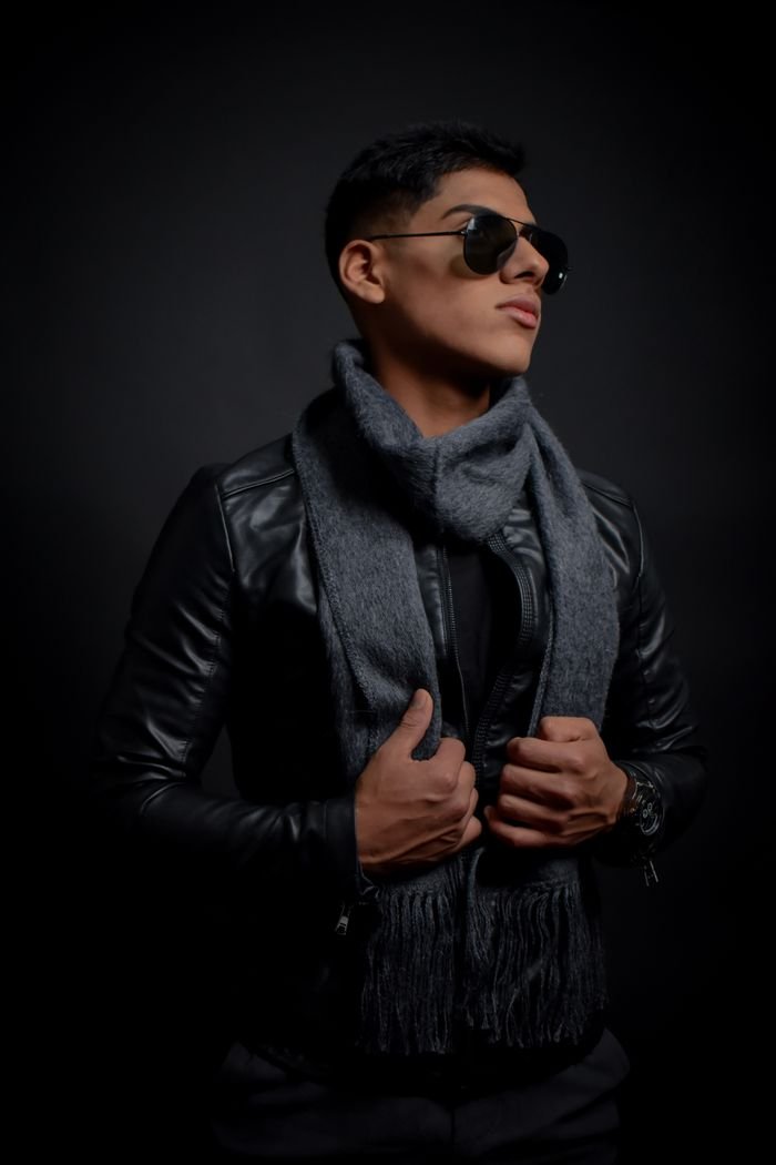 Portrait of a fashion-forward man in a leather jacket and scarf, exuding confidence.