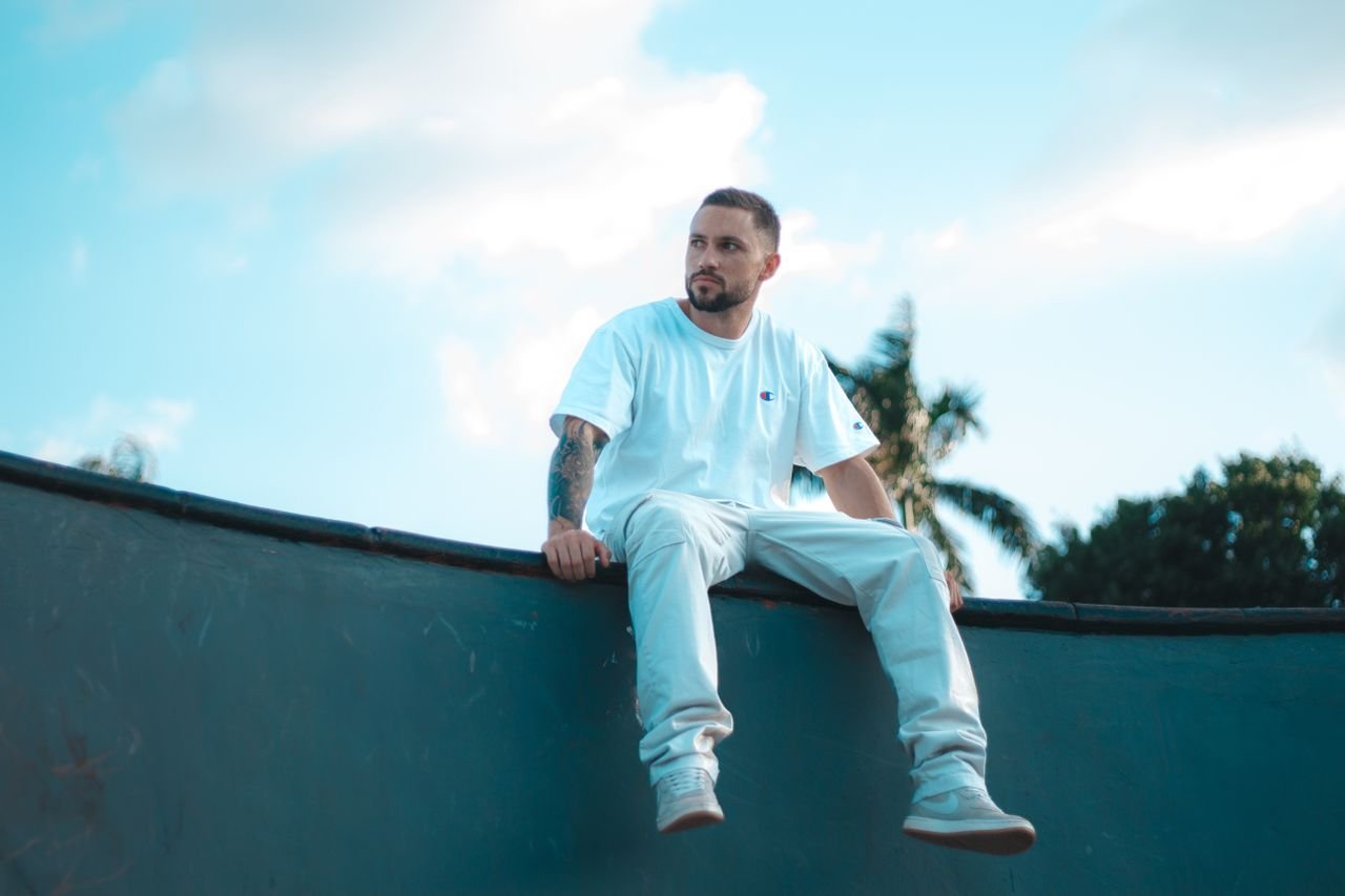Man in white t-shirt and pants sitting on a skate ramp in Goiânia, Brazil.