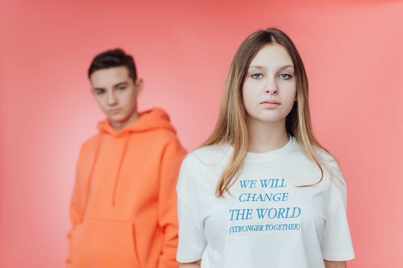 Young people in vibrant outfits promoting social change with empowering text on a t-shirt.
